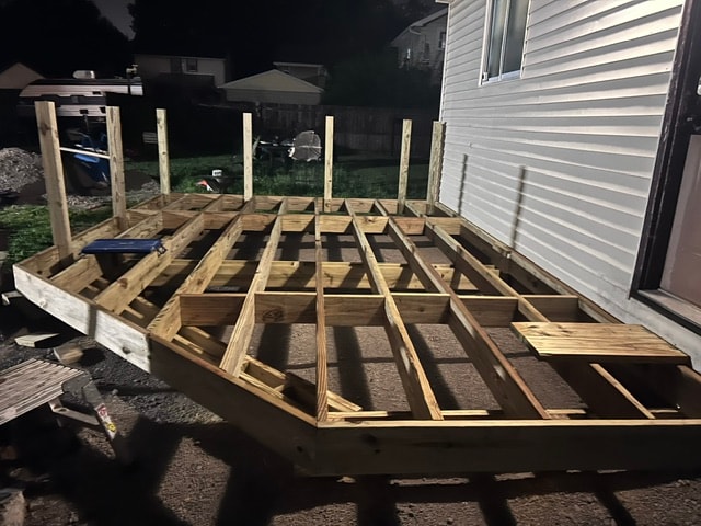 Deck substructure framing at night showing joists and posts