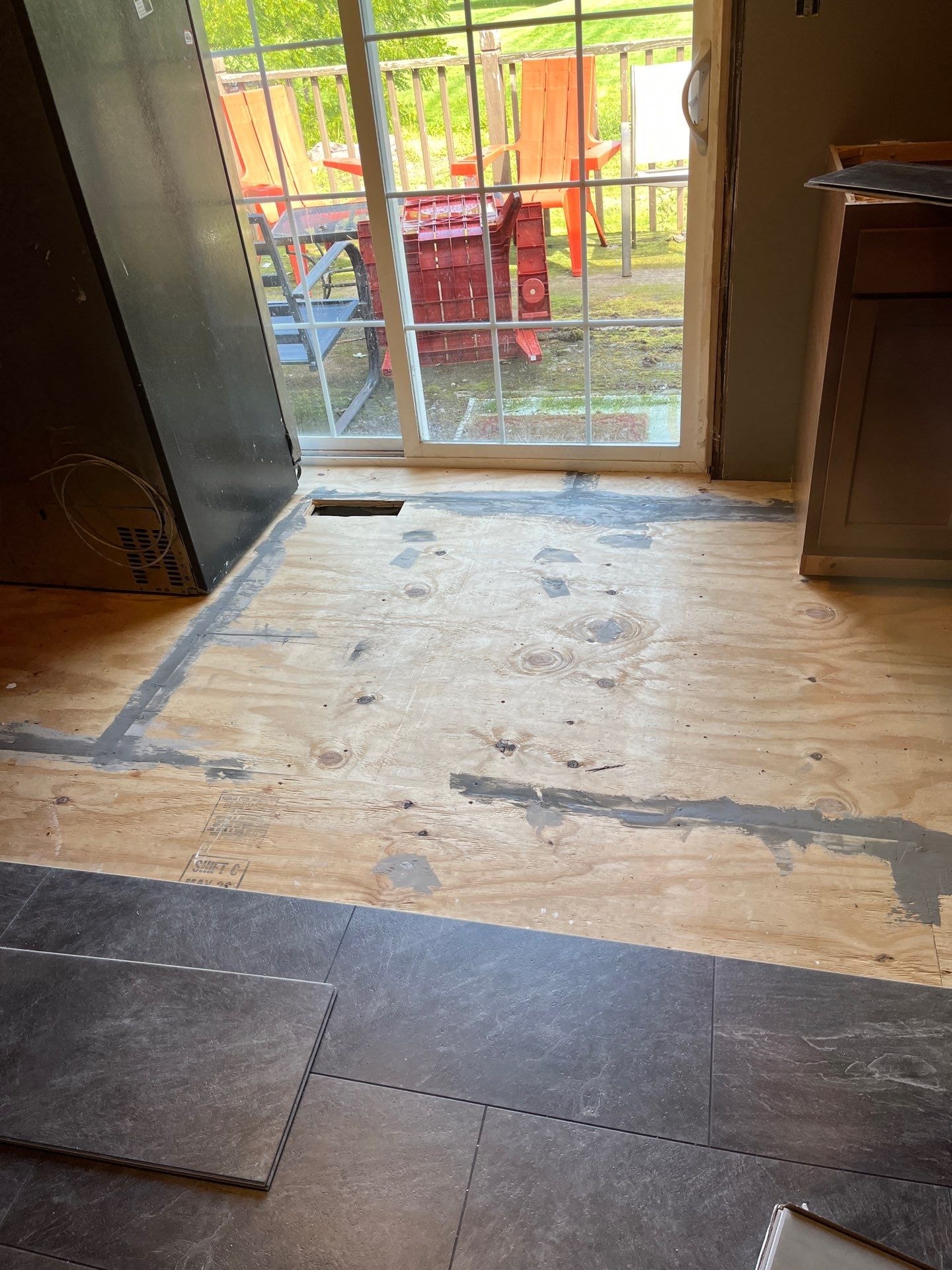 Tile-look LVP planks being laid at sliding glass door transition