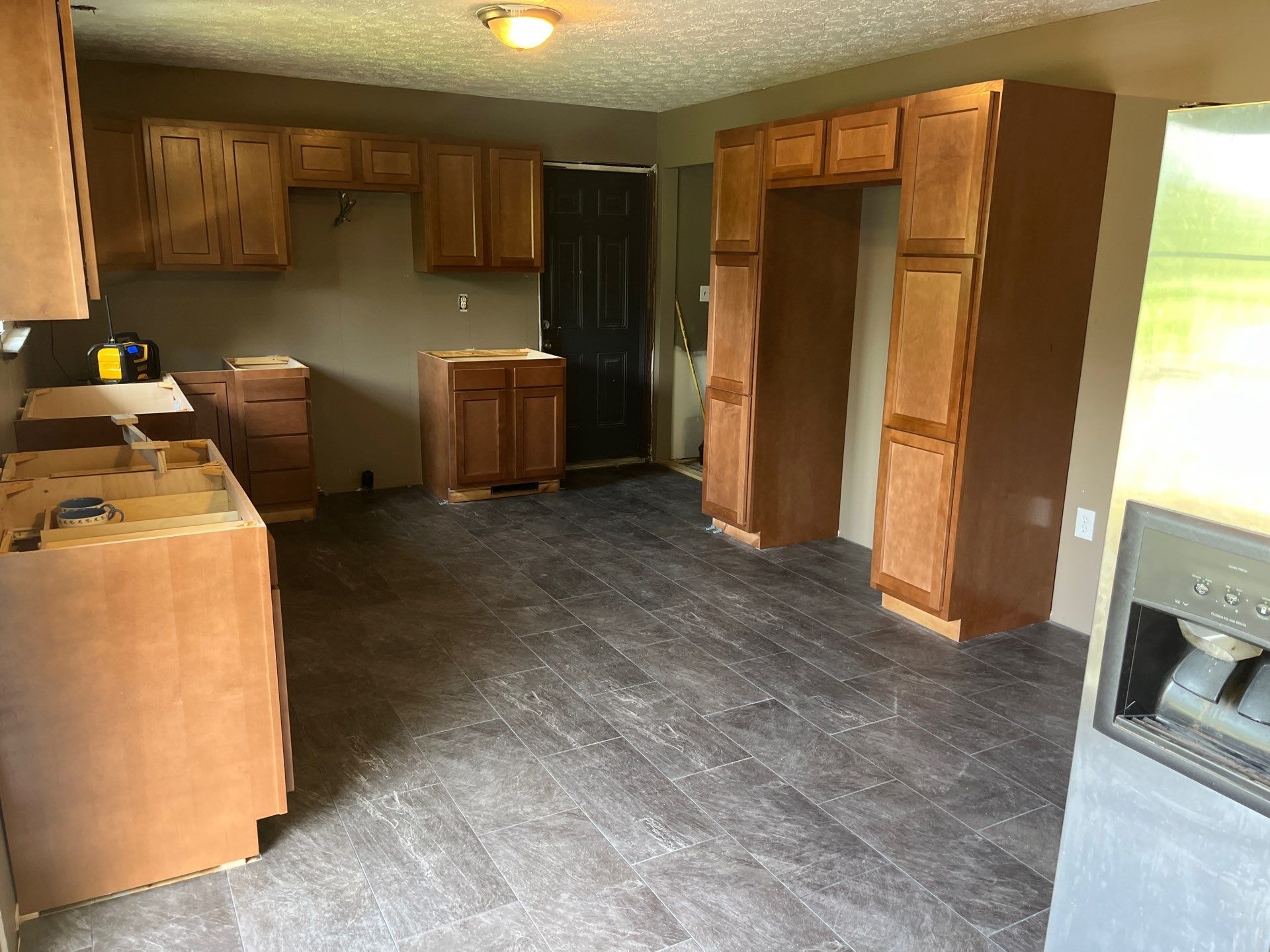 Completed tile-look LVP flooring in kitchen with new cabinets being installed